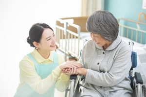 介護職員が高齢者の手を握りながら、思いやりのあるケアを提供している場面
